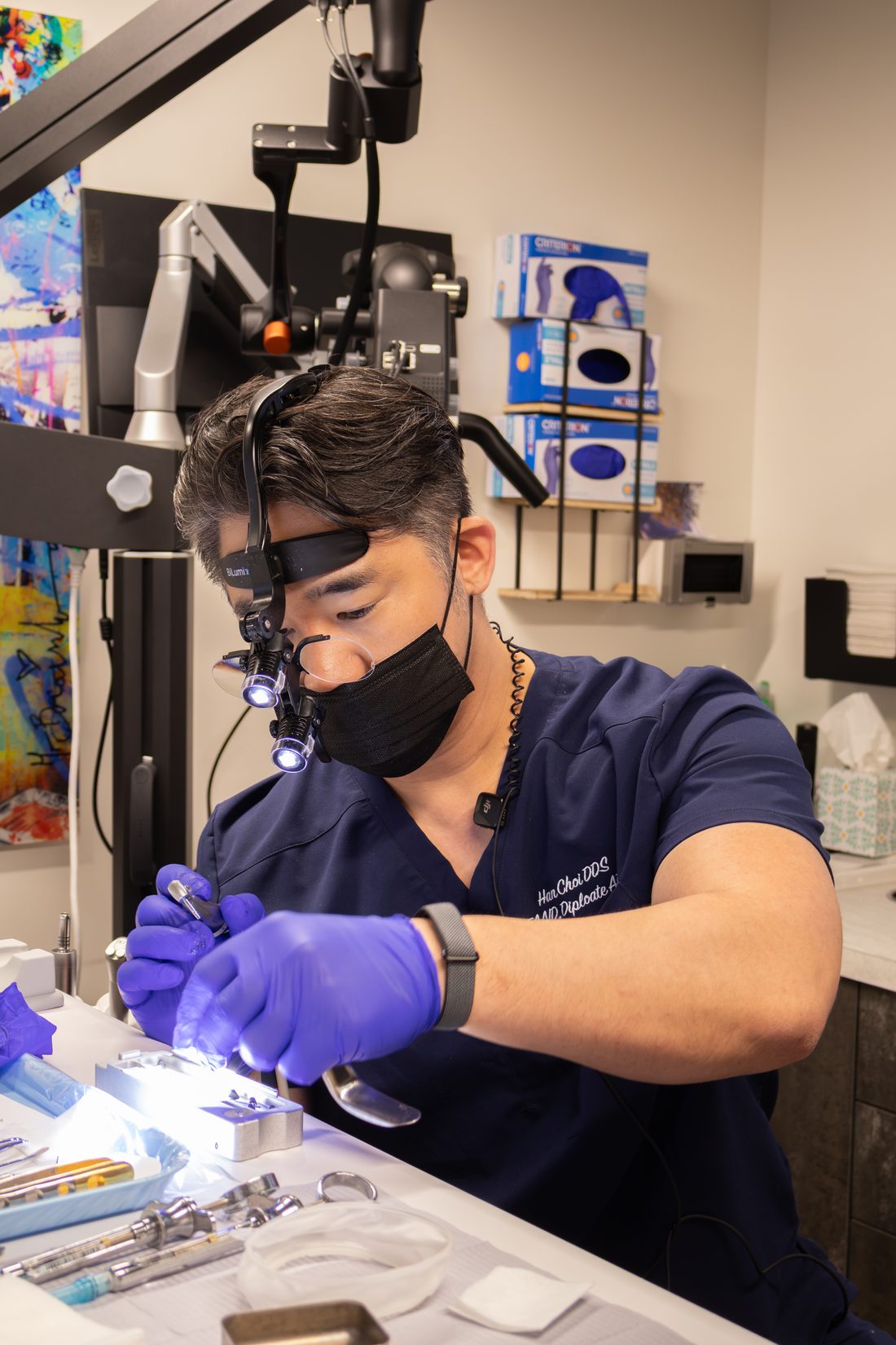 Dr. Han Choi wearing surgical loupes and a headlight, preparing implant instruments at a treatment tray.